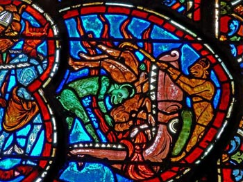 stained glass window showing devils dragging souls into the mouth of hell